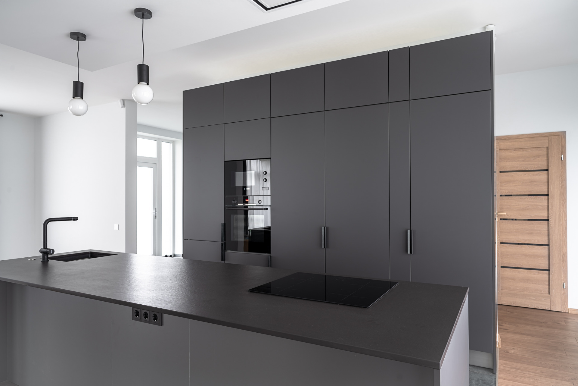 Кухонная мебель темно-серого цвета с матовыми фасадами и каменной поверхностью