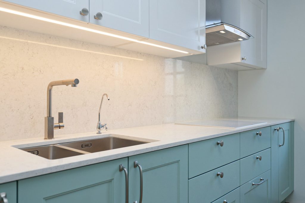 Kitchen furniture with white stone worktop and wall panel